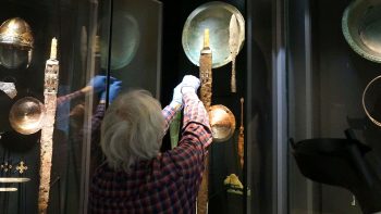 Restaurator Martin Raithelhuber entnimmt ein Objekt aus einer Vitrine der Schausammlung.