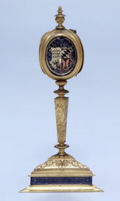 Goldene Prunkuhr mit von Ornamenten bedecktem Schaft. Das Uhrengehäuse zeigt auf einer Seite das württembergische Herzogswappen.