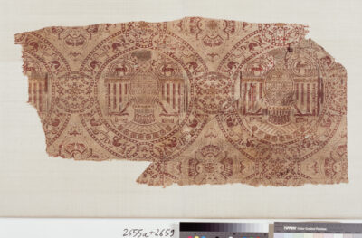 Ausschnitt eines Textils, stilistische Adler in runden Medaillions sind streng geometrisch nebeneinander angeordnet.