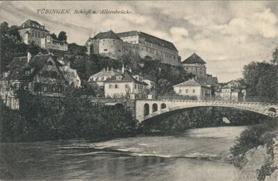 Alte Schwarz-weiß-Fotografie mit einem Fluss und einer Brücke. Dahinter ein Hügel mit vereinzelten Häusern und einem Schloss.