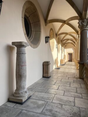 Gräuliche Steinsäule am linken Bildrand auf einem Arkadengang.