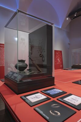 Blick in die Ausstellung, im Zentrum eine Vitrine mit metallzeitlichen Objekten. Ein Gefäß, ein Schwert und mehrere Schmuckstücke.