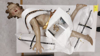 Skulptur eines Engels liegt auf einer gepolsterten Palette.