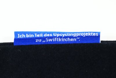 Ein Etikett mit der Aufschrift „Ich bin Teil des Upcyclingprojektes zu Swiftkirchen“.