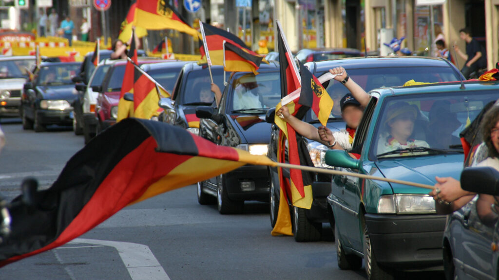 Menschen fahren Autos. Deutschland Fahnen werden durch offene Autofenster geschwenkt.