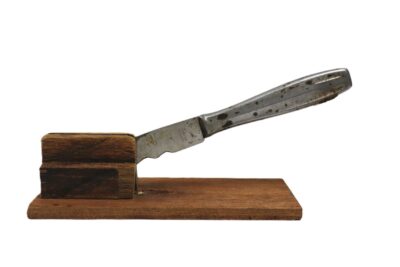 Selbstgebauter Nussknacker, bestehend aus einem Buttermesser, dessen Klinge zwischen zwei Holzklötzchen befestigt wurde.
