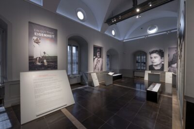 Blick in einen Ausstellungsraum mit Ausstellungsplakaten an den Wänden. 