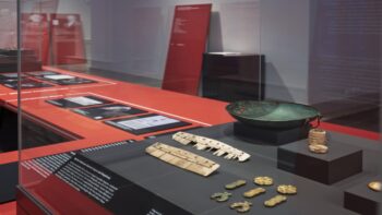 Blick in die Ausstellung. Im Zentrum eine Vitrine mit verschiedenen Objekten, wie Kämme und Zierelemente.