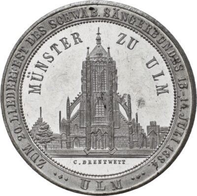 Eine Münze, auf der das Ulmer Münster abgesbildet ist und die Inschrift: "ZUM 20. LIEDERFEST DES SCHWÄB. SÄNGERBUNDES 13.–14. JULI 1884"
